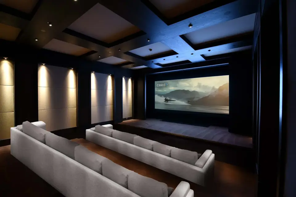 Cine privado con butacas en gradas y pantalla panorámica