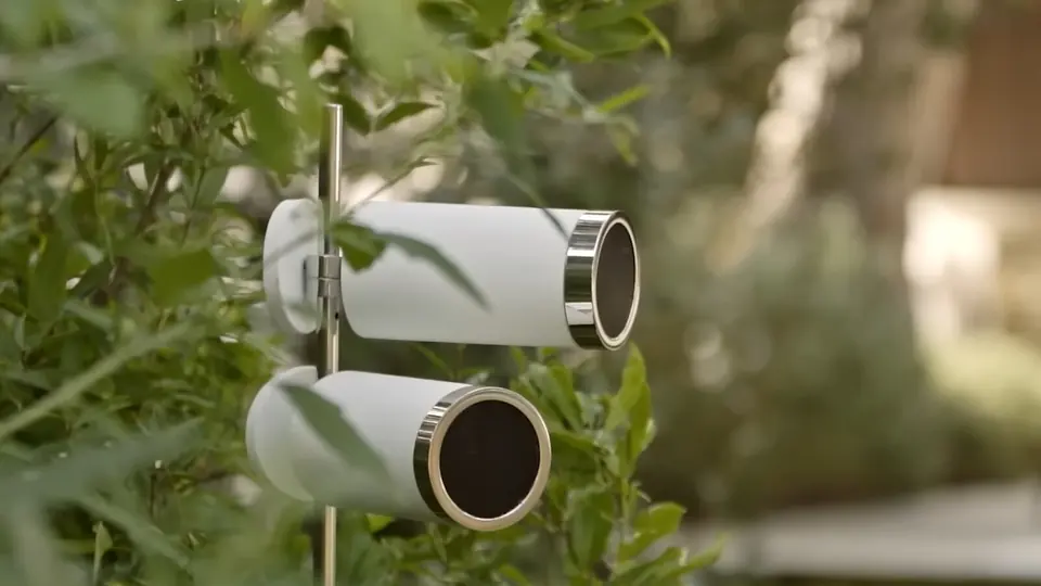 Bocinas de exterior Architettura Sonora: dos cilindros blancos montados en un poste entre la vegetación de un jardín.