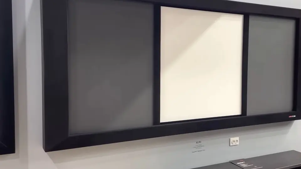 Pantalla Screen Research XLR3 en marco negro con enmascaramiento lateral, montada en un muro gris de exhibición.