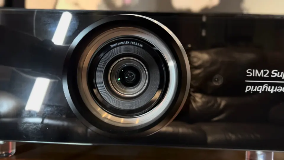 Lente del proyector SIM2 Crystal 4 Super Hybrid en primer plano, con el rótulo SIM2 Superhybrid en el chasis negro brillante.