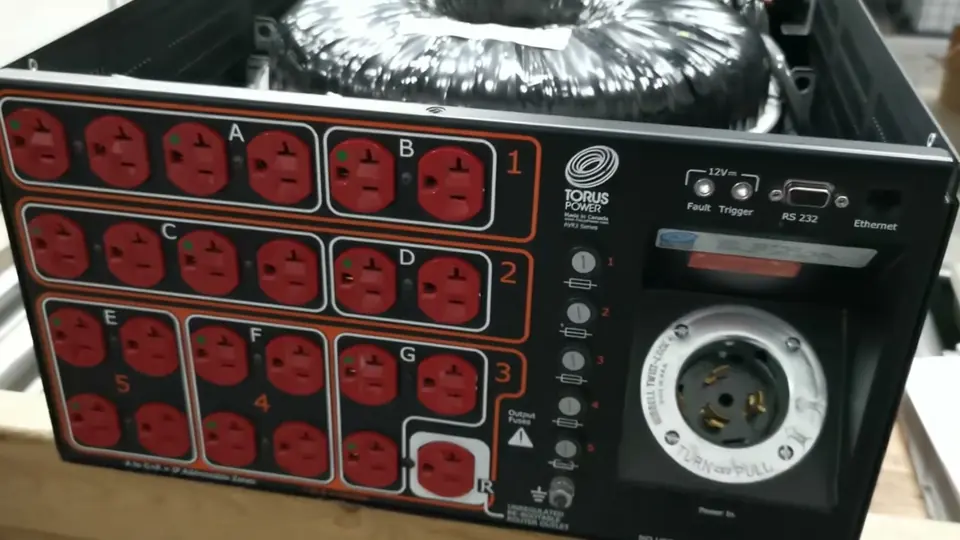 Acondicionador de energía Torus Power abierto: arriba, el transformador toroidal; al frente, el panel de contactos rojos agrupados por zonas y el conector de entrada.