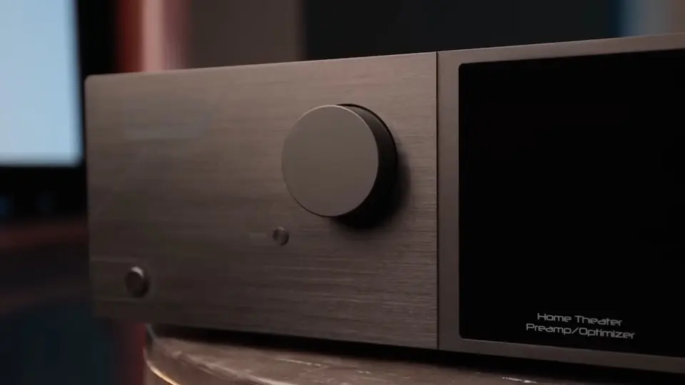 Procesador Trinnov Altitude visto de tres cuartos sobre madera, con su perilla de volumen y la pantalla frontal.