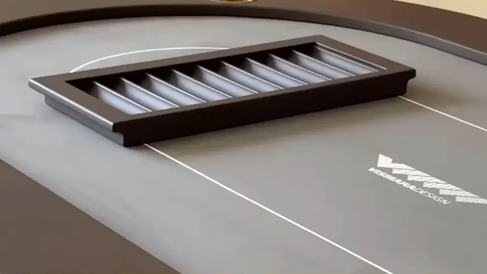 Mesa de póker Vismara Design: charolero de fichas en madera oscura sobre el paño gris con el logotipo de la marca.